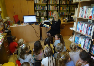 Dzieci siedzą wokół Pani Hofmann, która prezentuje książkę.